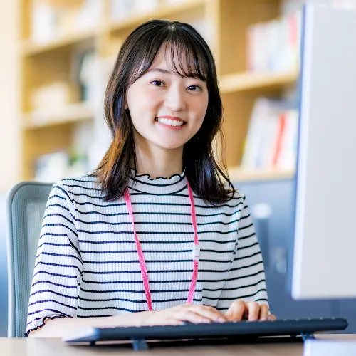 デスクに座り笑顔の女性スタッフ
